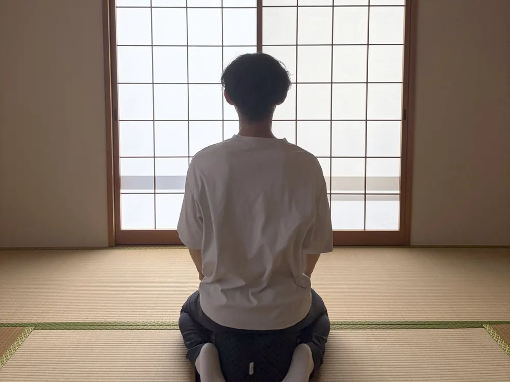 サロンの和室で障子に向かい、床に座って行う座る瞑想